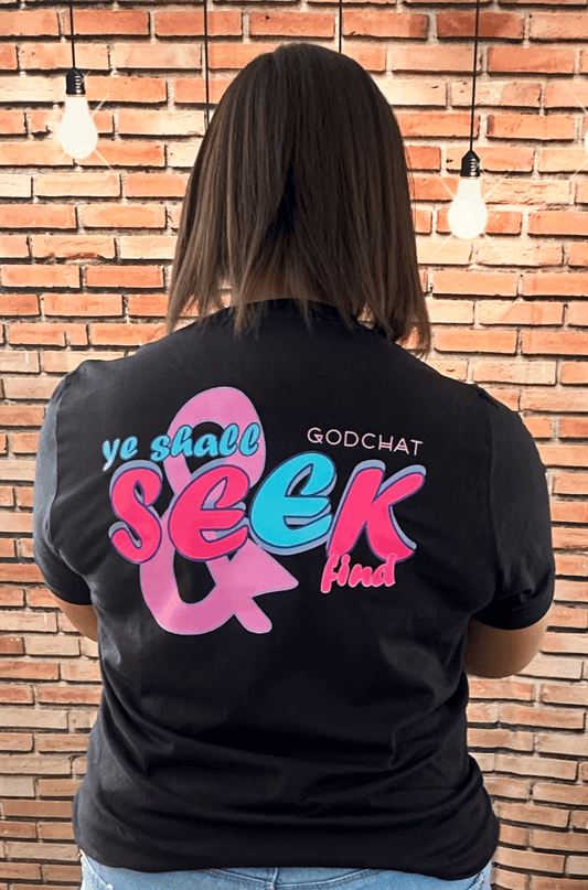 FEMALE WEARING BLACK SEEK AND YE SHALL FIND TEE WITH PINK AND BLUE DESIGN! BACK OF SHIRT.